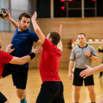 Match de handball en salle avec chronomètre et joueurs en action