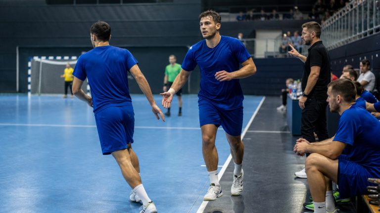 Remplacement de joueurs pendant un match de handball dans la zone de changement, près du banc.