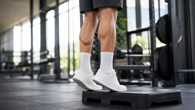 Exercice de musculation des mollets sur une marche dans une salle de sport lumineuse